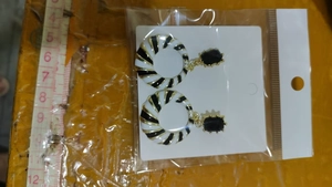 Detail of geometric black and white polka dot drop earrings with ruler for size reference