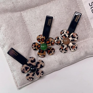 Three leopard print acetate flower hair clips with colorful centers and rhinestones
