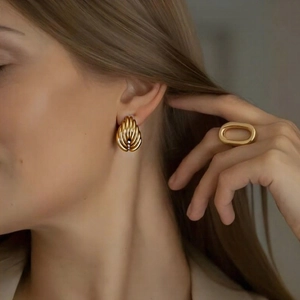Textured gold-tone shell earrings and hollow oval ring on a fashion model