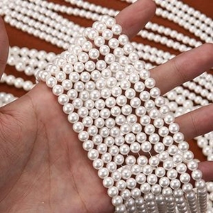 Close-up of high-luster white round pearls held by hand for DIY jewelry making