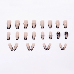 Long nude French press-on nails with black bow and rhinestone details in a 24-piece set