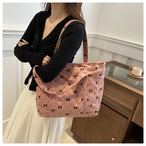 Rosa Cord-Einkaufstasche mit schwarzem Schleifenmuster an einem Model im Café-Stil