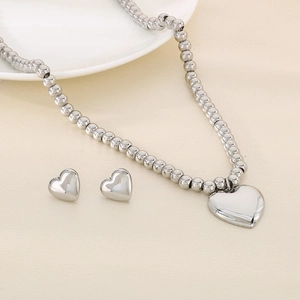 Macro detail of silver stainless steel heart pendant and beaded necklace with matching studs