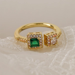 Close-up of gold-plated ring with emerald green stone on white lace fabric