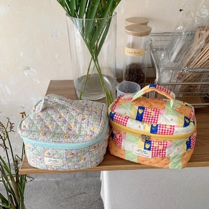 Trousses à maquillage en coton matelassé à fleurs et carreaux sur table en bois