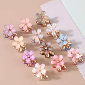Macro detail of resin flower hair claws with pearls and glitter on golden clips