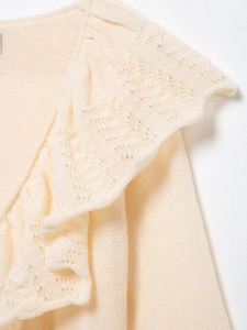 Detailed close-up of cream knit sweater featuring layered ruffles and hollow-out lace patterns