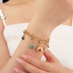 Gold beaded bracelet with natural colorful stone pendants on a woman's wrist