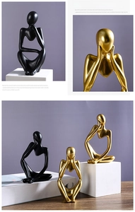 Detail of Nordic abstract thinker statues in matte black and gold finish on stone base