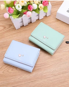 Close-up of small tri-fold PU leather wallets in light blue and mint green with heart hardware