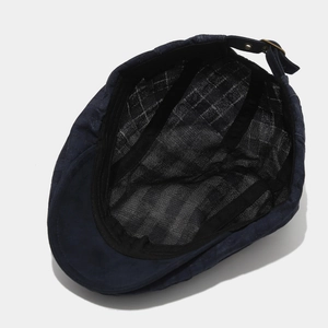 Detail view of the navy newsboy cap featuring mesh lining and adjustable metal buckle