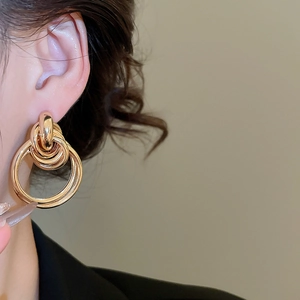 Vue macro de boucles d'oreilles anneaux entrelacés dorés portés par un mannequin