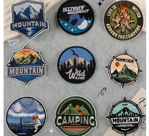 Macro shot of 9 circular mountain and camping embroidery patches for outdoor clothing decor