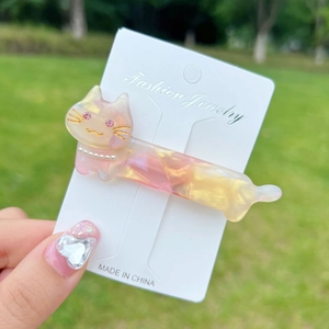 Close-up of cute cat hair clip with pink gradient finish and pearl detail on card