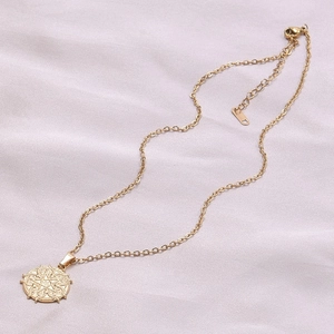 Detail of 18k gold plated stainless steel star pendant on purple silk fabric