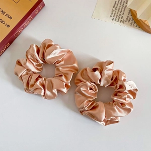 Close-up of champagne satin scrunchies set with a silky texture and elegant folds