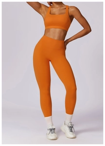 Detail view of bright orange high-waist yoga leggings and U-neck sports bra set