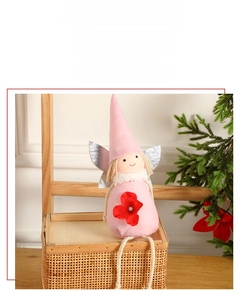 Détail d'une poupée ange de Noël rose en peluche avec ailes argentées sur un panier