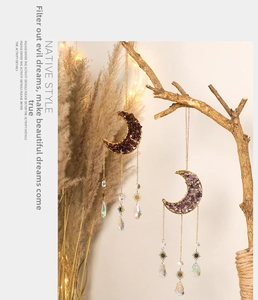 Moon-shaped crystal suncatcher with amethyst stones and metal stars in a cozy natural setting