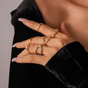 Close-up of gold geometric rings with rope texture and irregular curves on hand