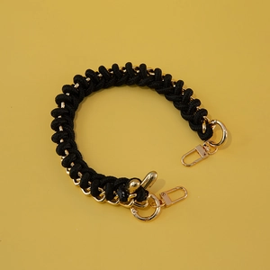 Detail of black woven rope and gold metal chain strap with lobster clasps on yellow background