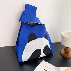 Close-up of blue knitted tote bag featuring a cute black and white panda pattern