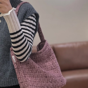 Dettaglio della trama in tweed viola e dell'etichetta in tessuto della borsa a spalla