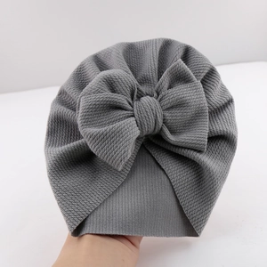 Close-up of grey baby turban hat with oversized bow detail in soft knitted fabric