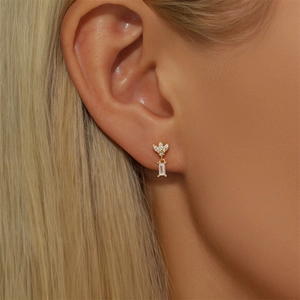 Close-up of a model wearing a gold infinity shaped earring with marquise cut zircons