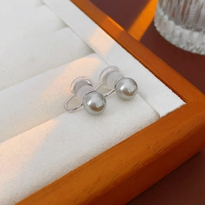 Detailed view of silver grey pearl ear clips resting on white velvet jewelry box padding