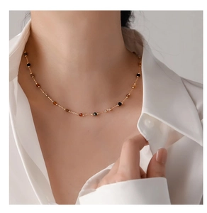 Close-up of a minimalist gold necklace with colorful natural stone beads on a model