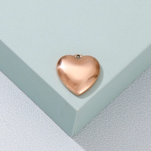 Detailed view of a polished rose gold heart pendant on a modern geometric display