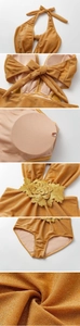 Detail view of gold metallic swimwear showing 3D floral embroidery and halter bow