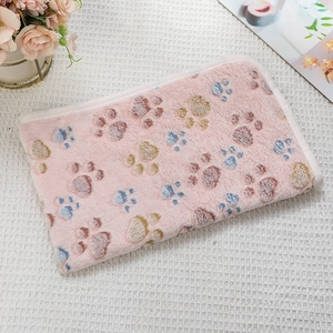 Detailed view of pink flannel pet blanket with colorful paw prints on checkered surface