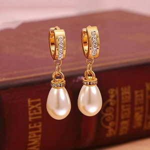Detailed close-up of gold drop earrings with micro-set diamonds and large white teardrop pearls