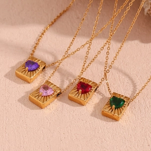 Macro shot of four gold card pendants with multi-colored heart-shaped zircons and fine chains