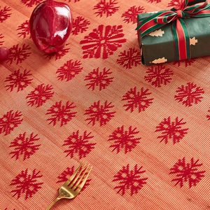Close-up of red woven Christmas table runner with festive snowflake patterns and table decor