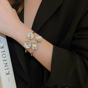 Detail of a minimalist gold cuff bracelet with four large round zircon stones on a model