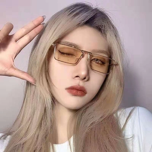 Close-up of golden metal rectangular sunglasses with transparent yellow lenses on model