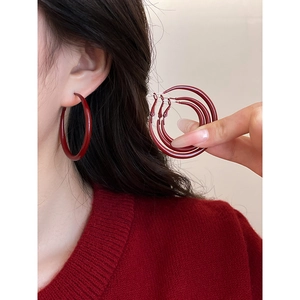 Detail of four pairs of glossy red round hoop earrings in various sizes for women