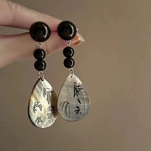 Makrodetail von chinesischem Muschelohrring mit Bambusmuster und irisierendem Glanz