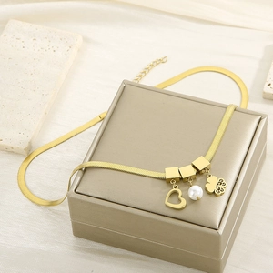 Detailed close-up of golden snake chain necklace with heart, pearl, and floral pendants