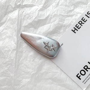 Close-up of silver PU leather hair clip with three star rhinestones on textured paper