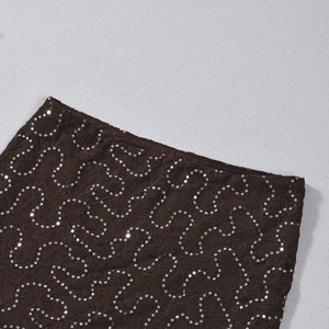 Detail shot of dark brown lace fabric featuring dense silver sequins and waist stitching