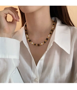 Détail du collier de perles avec pierres œil de tigre et perles dorées sur un mannequin