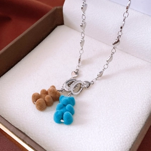 Détail macro de pendentifs oursons floqués marron et bleu dans un coffret cadeau