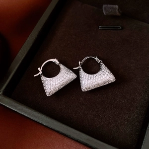 Macro shot of silver zircon pavé bag-shaped earrings in a black velvet jewelry box