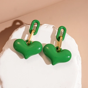 Macro shot of vibrant green heart earrings with gold links on a stone pedestal