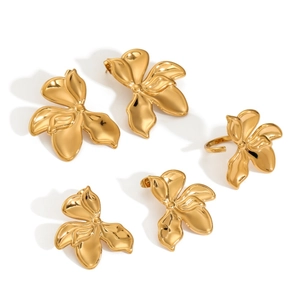 Close-up view of gold-plated stainless steel flower jewelry set including earrings and ring.