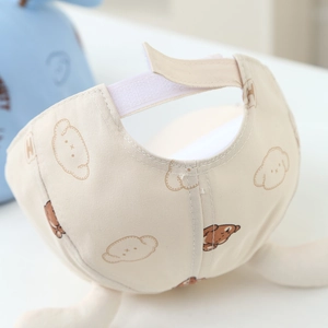 Detail view of adjustable velcro strap on a beige infant hat with cute bear prints